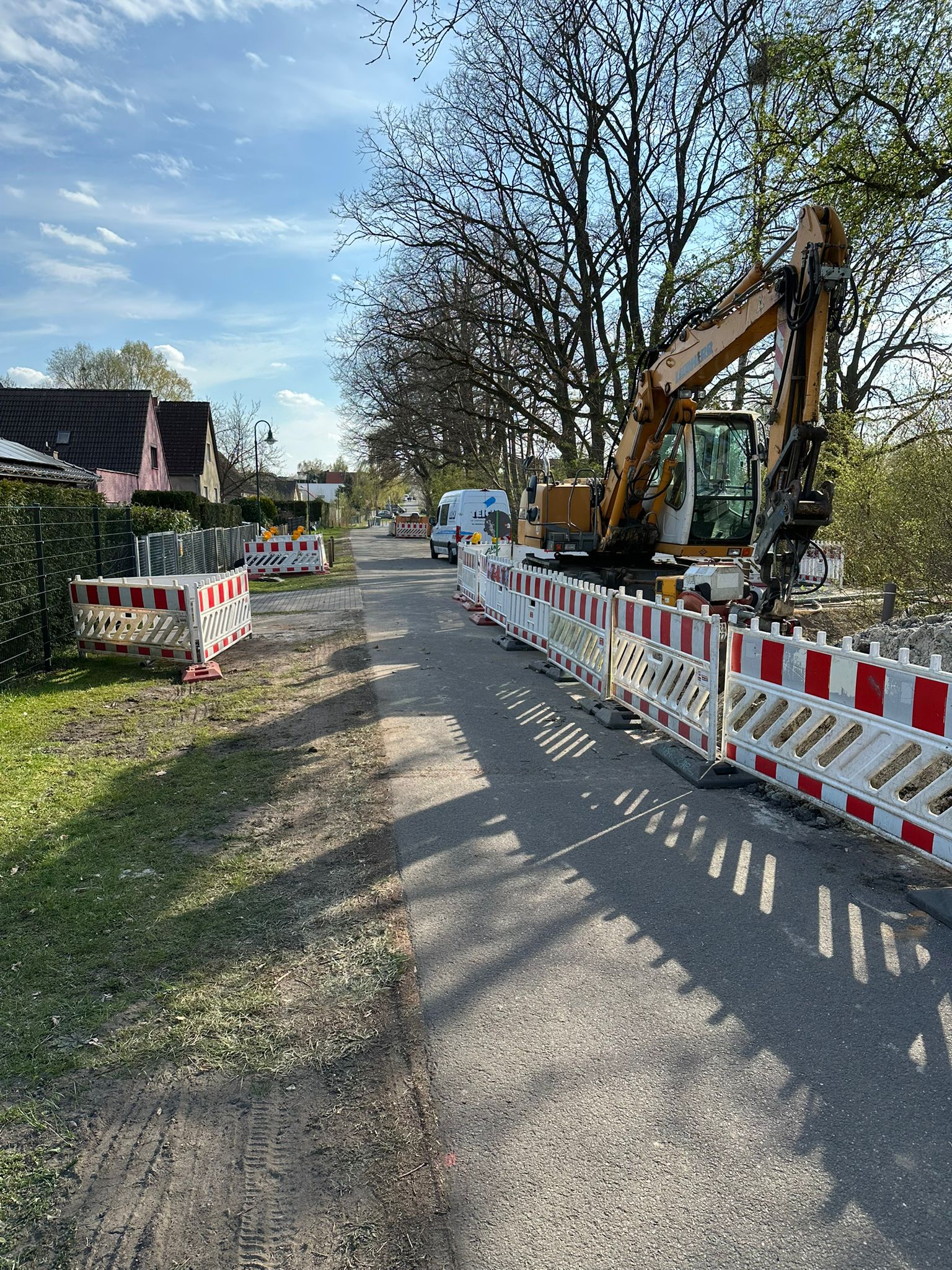 Gelber Bagger ohne Fahrer, ruhig, an Baustelle mit rot weißen Absperrungen