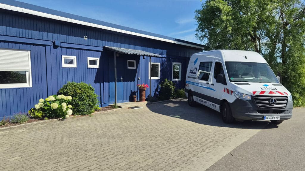 Blaues Gebäude mit freundlichem Eingang und weißem Lieferwagen davor
