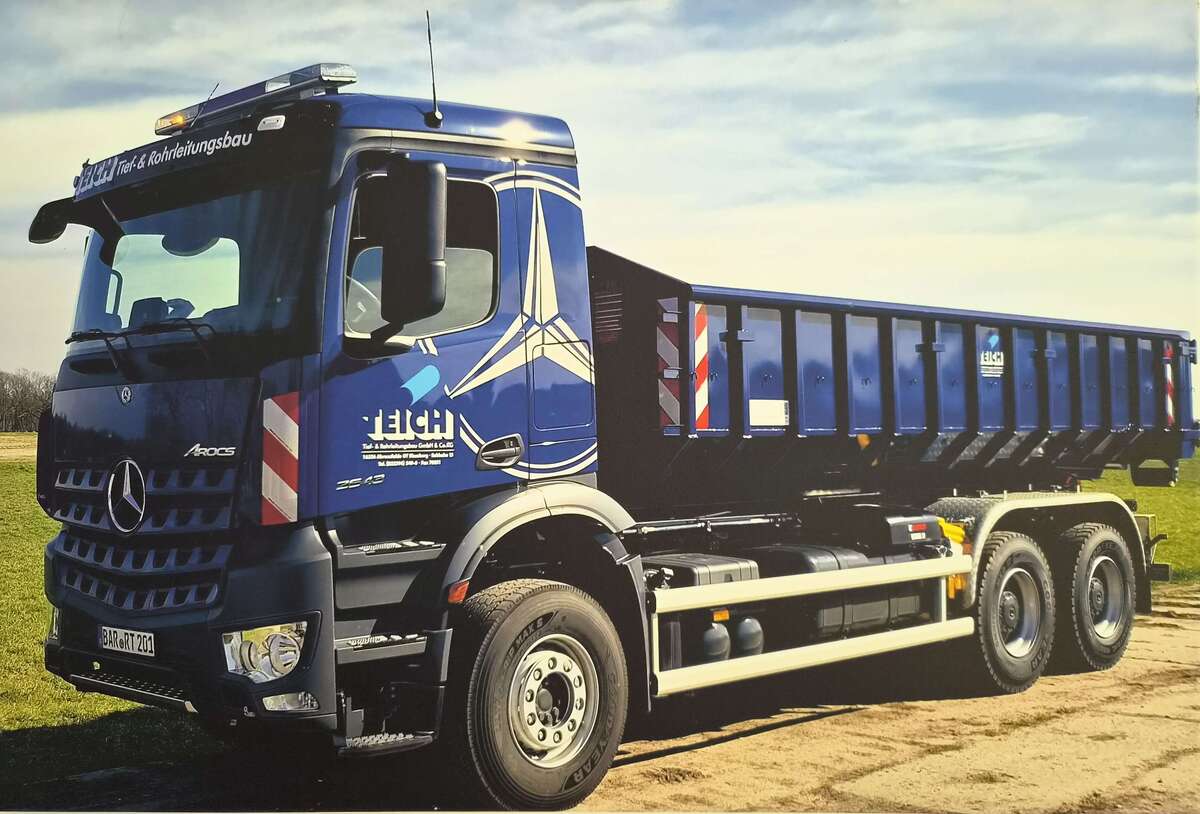 Blauer Mercedes Arocs Lastwagen der Firma Eich mit Container auf Feldweg