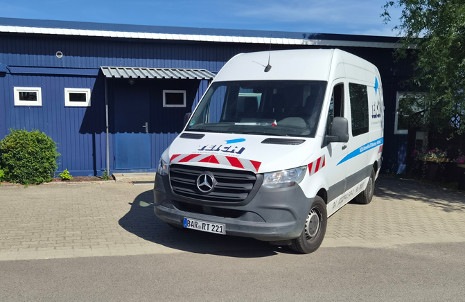 Weisser Mercedes Transporter mit blauem Logo vor blauer Lagerhalle